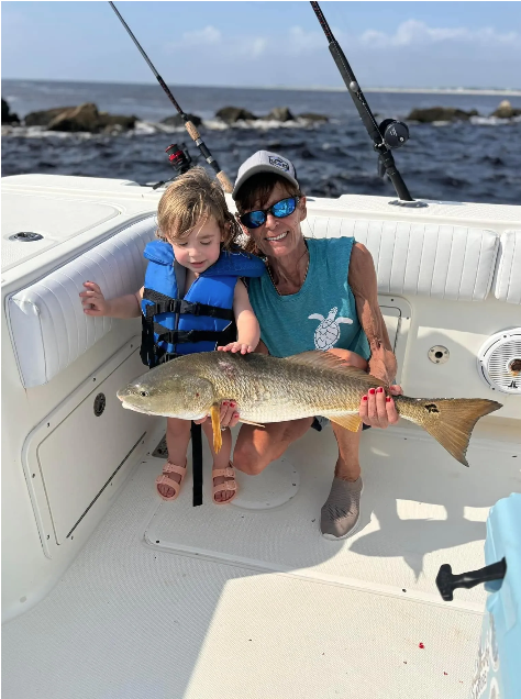 Mother and child holding a redfish catch aboard a D&R Charters fishing trip