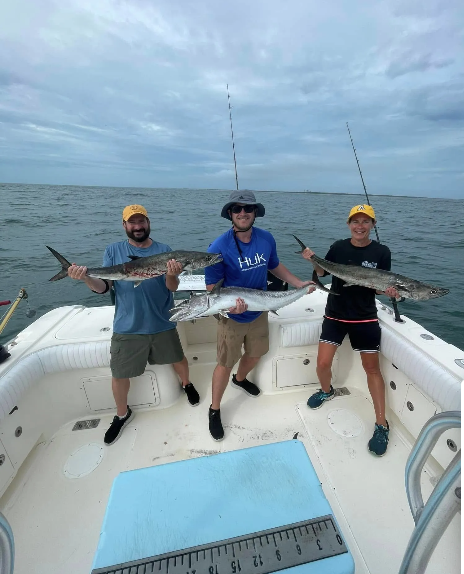 Three anglers holding a king mackerel catch aboard the Ring Money