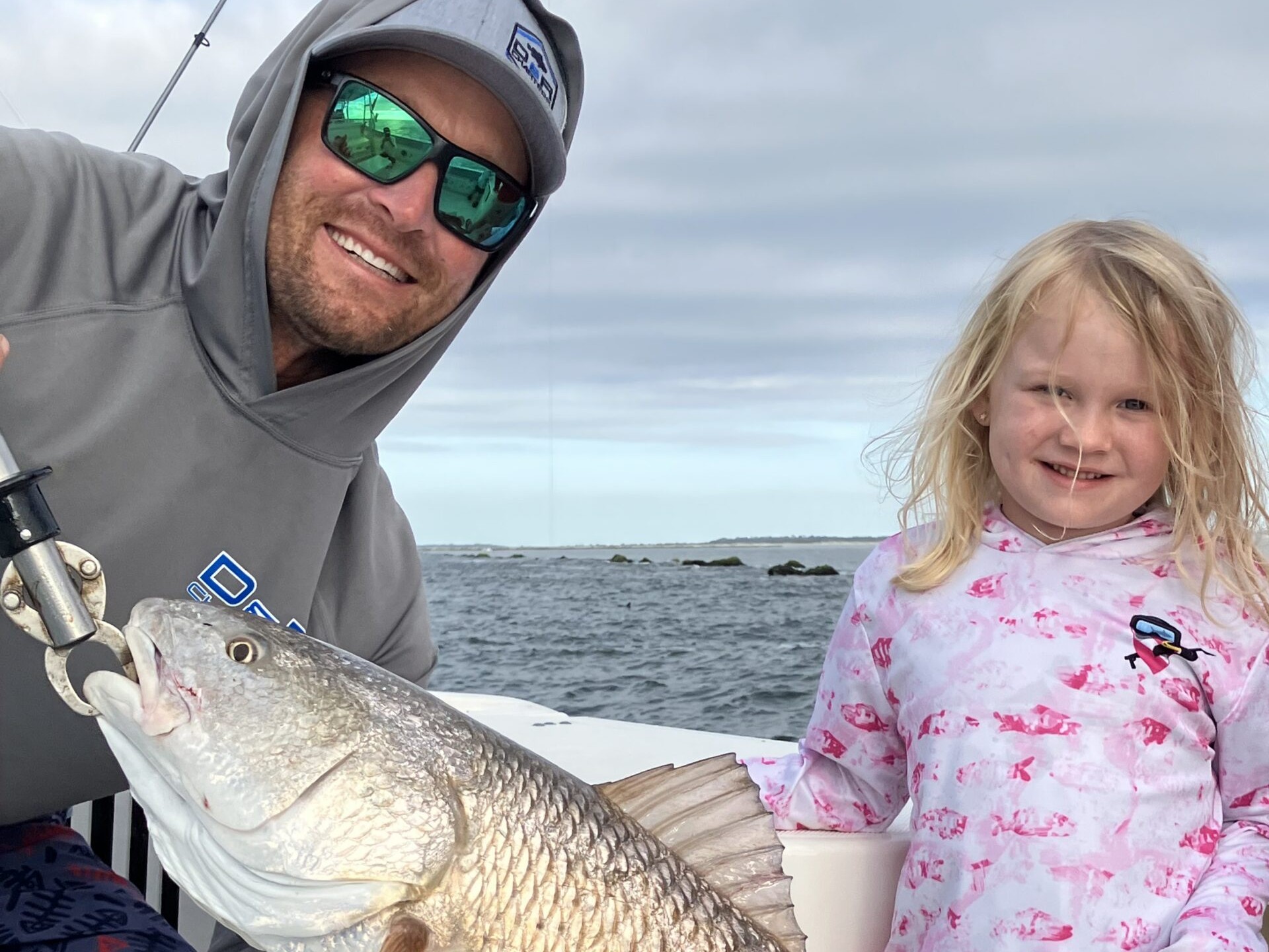 Father and daughter with a redfish catch near the jetty rocks